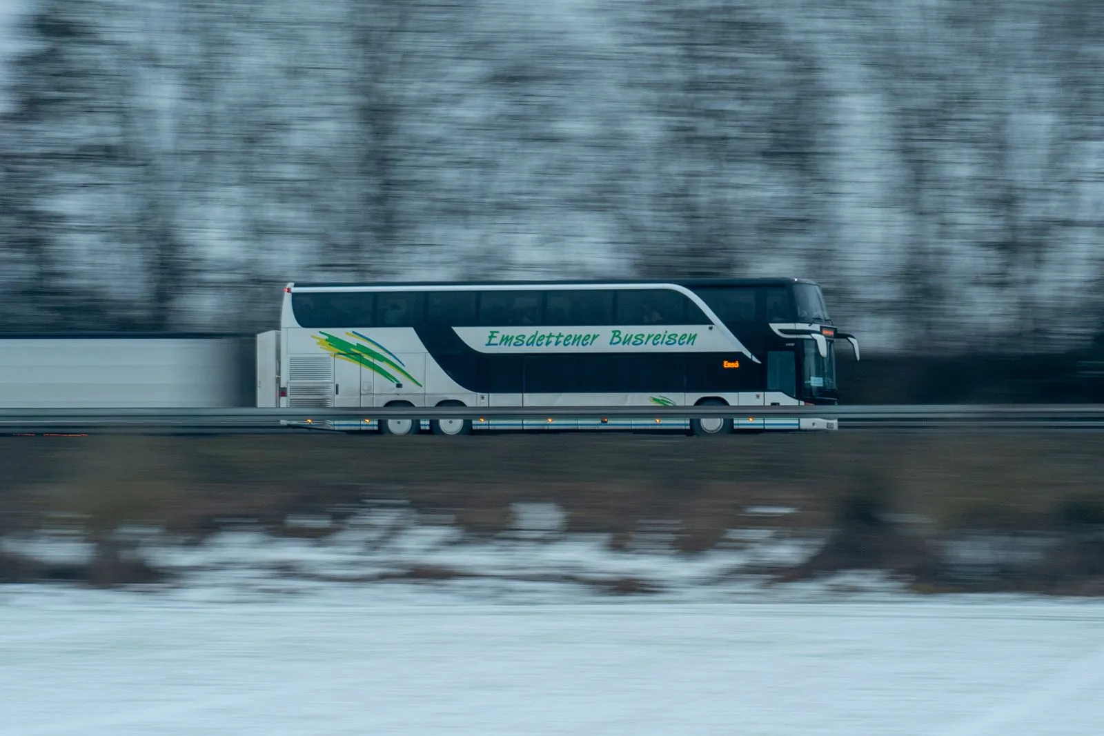 Un pullman a due piani in corsa su una strada innevata