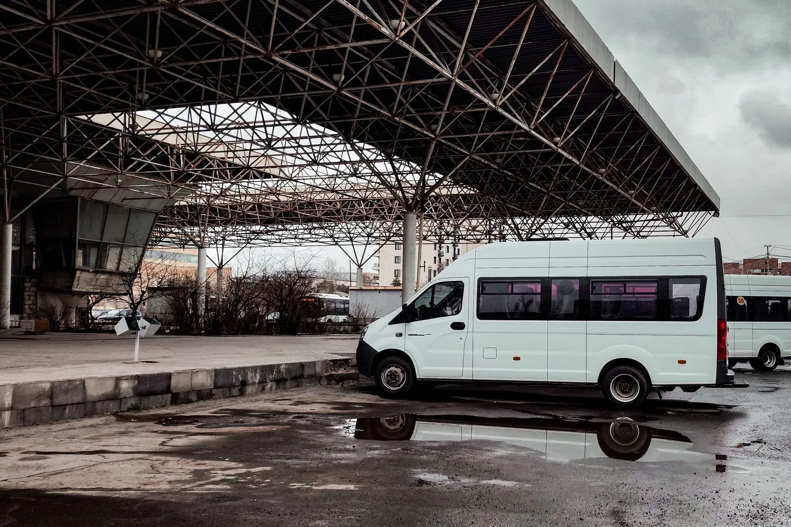 Un minibus bianco fermo sotto la pensilina di una stazione delle corriere