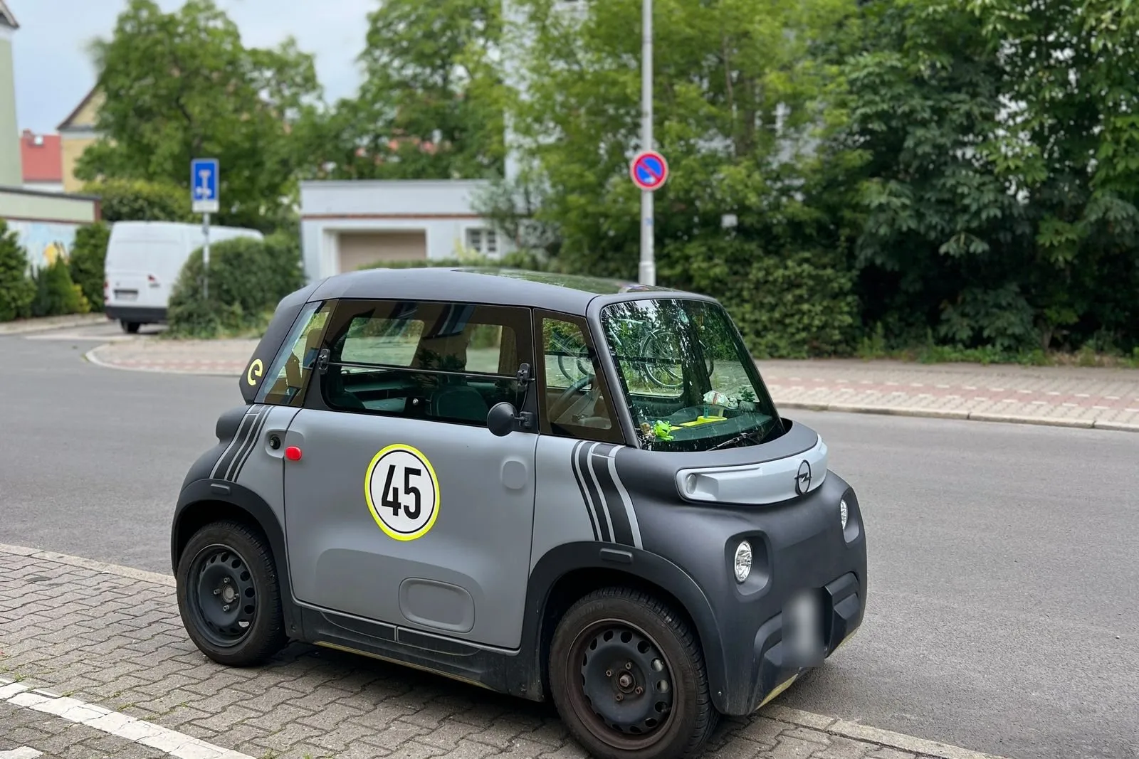 Una minicar elettrica grigia a due posti, col bollino dei 45 km/h sulla portiera