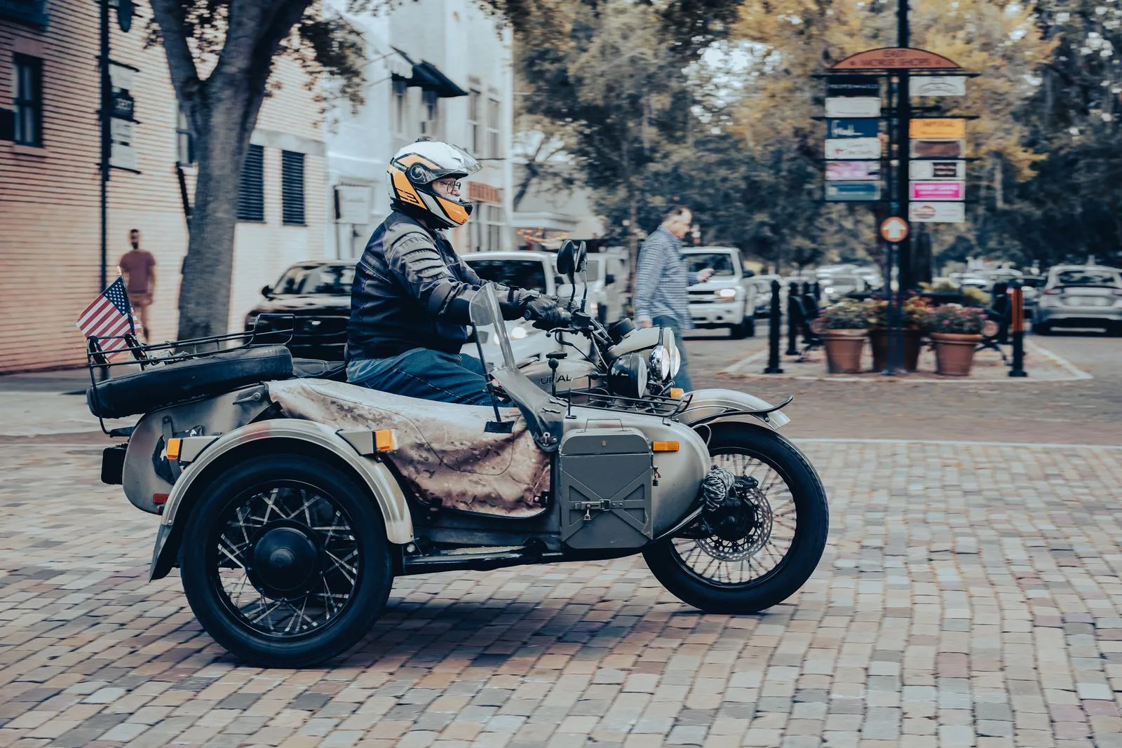 Un motociclista col casco su una moto con sidecar, in una strada di città